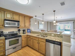 a kitchen with wooden cabinets and stainless steel appliances at Silver Seas 103 in Tybee Island