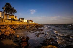 a beach with rocks and buildings and the ocean at Lower Bouys in Seaview