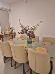 un tavolo da pranzo con sedie e un vaso con fiori di Casa del Mare a Wattala