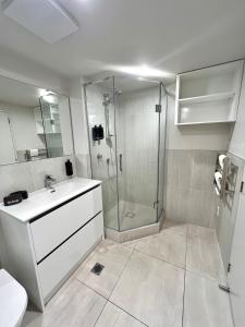 Un baño blanco con ducha y lavabo. en 6 on Adams, en Mount Maunganui 60 fotos más