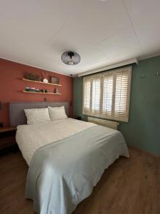 Un dormitorio con una cama blanca grande y una ventana en Cozy escape near Den Bosch - 4 PS chalet met veel privacy en rust!, en Lith 41 fotos más