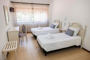 a room with two beds and a chair and a window at Residencial San Fernando in Ponte da Barca