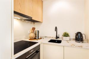 Una pequeña cocina con gabinetes blancos y un fregadero. en BLQ Charneco 1BDR in Boliqueime by LovelyStay, en Boliqueime 3 fotos más