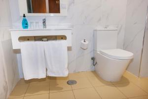 a bathroom with a toilet and a sink with towels at Residencial San Fernando in Ponte da Barca