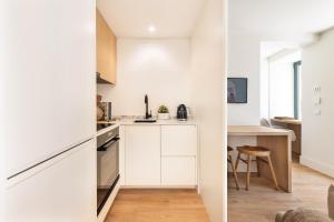 una pequeña cocina con armarios blancos y una mesa en BLQ Charneco 1BDR in Boliqueime by LovelyStay, en Boliqueime