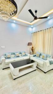Una sala de estar con dos sofás y un ventilador de techo. en Orchid Highland, en Dehradun