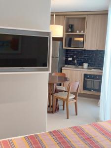 a living room with a television and a kitchen at Unique Residence Lindo Apartamento Vista Mar e garagem in Santos