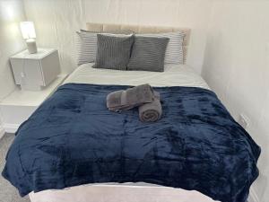 een bed met een blauw dekbed en handdoeken erop bij Zinoc Seaside Apartment in Murton