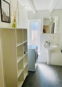 a bathroom with a sink and a washing machine at L'Escapade Charentaise Central et calme in La Rochefoucauld