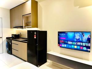 a kitchen with a black refrigerator and a flat screen tv at Majestic Residence KLCC By Homestay in Kuala Lumpur