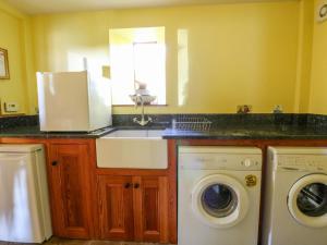 a kitchen with a sink and a washing machine at Maggie's Barn in Talgarth