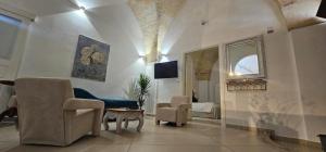 een woonkamer met een bank, stoelen en een spiegel bij Volta Apartment in Mesagne