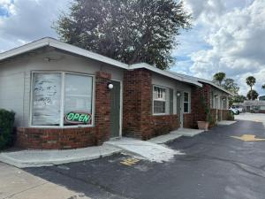 Holly HillRollie's Motel Daytona Beach by Hotel O的一栋挂着“营业中”牌子的砖砌小楼