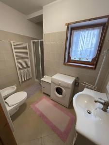 un bagno con lavandino, WC e finestra di Tabià Padola a Comèlico Superiore Altre 7 foto