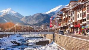 a street in a town with a river and snowy mountains at Best Central Lux Studio in Bansko