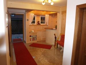 - un couloir avec un tapis rouge au sol dans l'établissement Garni Flurida, à Selva di Val Gardena