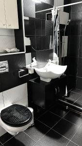 un bagno bianco e nero con lavandino e servizi igienici di Walk-In Promenada a Craiova