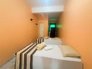 three beds in a room with orange walls at Hotel Coutinho PIO XII in Pirapora