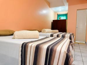 a room with two beds with striped sheets at Hotel Coutinho PIO XII in Pirapora