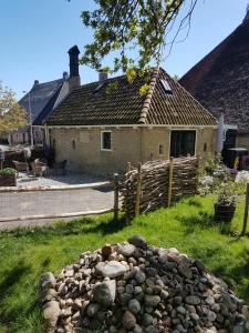 a house with a fence and a pile of rocks at Âlde Bakhûs in Sondel