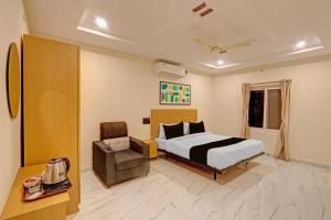 a hotel room with a bed and a chair at Super Townhouse SP Living Tree in Karīmnagar