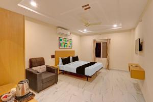a hotel room with a bed and a chair at Super Townhouse SP Living Tree in Karīmnagar