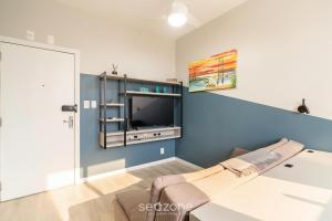 sala de estar con pared de acento azul y TV en Apto 1 Dormitorio en el Centro de Floripa EFO0603, en Florianópolis