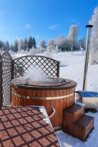 a hot tub with snow on the ground at Domov na horách - Krkonoše - horký sud, pergola, dětské hřiště - celý dům in Mřičná