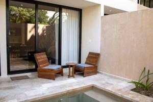 图卢姆Peregrina Tulum 102A 2BR Luxury Condo的庭院设有两把椅子和一张桌子,庭院内设有游泳池