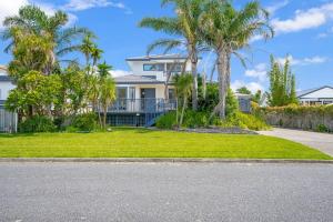 a house with palm trees in front of a yard at Seaside Premium Home with Spa Pool near Beach in Beachlands