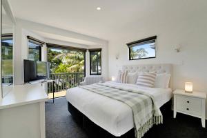 a white bedroom with a bed and a balcony at Seaside Premium Home with Spa Pool near Beach in Beachlands