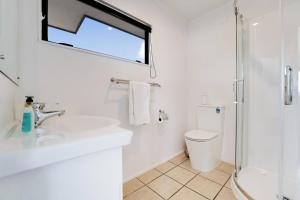 a white bathroom with a sink and a shower at Seaside Premium Home with Spa Pool near Beach in Beachlands +27 photos