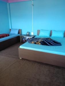 a bedroom with two beds with a blue background at Susanta Homestay , Icchegaon , Kalimpong in Kalimpong
