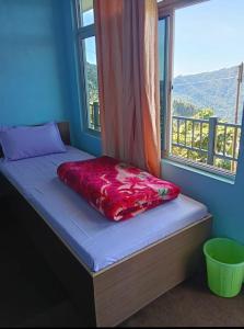 a bed in a room with a window at Susanta Homestay , Icchegaon , Kalimpong in Kalimpong +3 photos