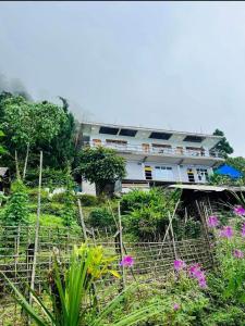 a building on the side of a hill with flowers at Susanta Homestay , Icchegaon , Kalimpong in Kalimpong
