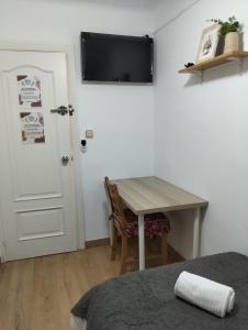 a room with a table and a television on the wall at Alojamiento Calma in Hospitalet de Llobregat