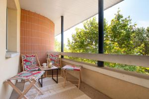 图卢兹PinkCity Signature - air conditioning - metro - parking - patio的阳台配有两把椅子和一张桌子,还有一个窗户。