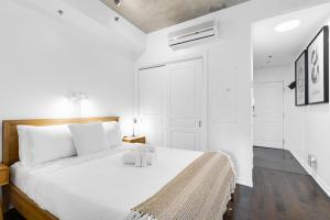 una camera bianca con un grande letto con cuscini bianchi di Pristine Parc Avenue Pad With Parking a Montréal