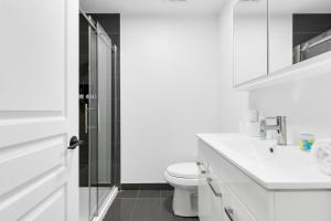 un bagno bianco con wc e doccia di Pristine Parc Avenue Pad With Parking a Montréal Altre 21 foto