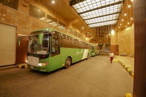 two buses parked in a building with a person walking by at Abraj Al Tayseer Tuwa Hotel in Makkah