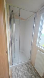 a shower with a glass door in a bathroom at 17 Ruby Atlas Monreith in Monreith +17 photos
