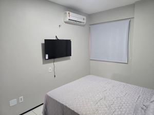 a white bedroom with a bed and a flat screen tv at Flat Biarritz - Praia Litorânea in São Luís