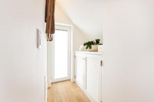 Un pasillo blanco con una puerta y una planta en un armario. en BLQ Charneco 1BDR in Boliqueime by LovelyStay, en Boliqueime