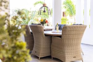 Un comedor con una mesa y sillas de mimbre. en Goudhaen Luxury Private apartments Jan Thiel Beach, en Jan Thiel