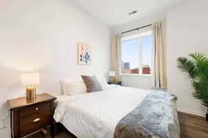 a white bedroom with a large bed and a window at Spacious 3BR Urban Getaway w Gym in Chicago