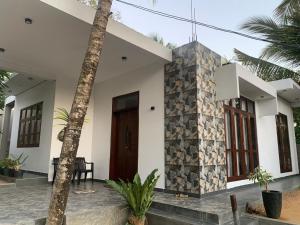 HiriketiyaにあるDasis villaの木の扉とヤシの木がある白い家