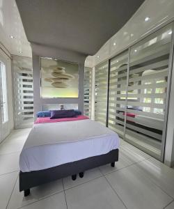 a bedroom with a large bed and large windows at Villa Paradiso by Monarca Prestige in Furiani