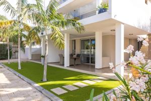 una vista exterior de una casa con césped y palmeras en Goudhaen Luxury Private apartments Jan Thiel Beach, en Jan Thiel