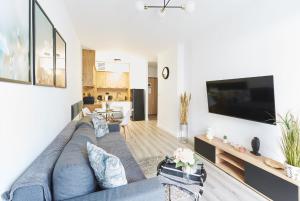 Una sala de estar con un sofá azul y un televisor de pantalla plana. en SkyTravel 26 Apartament Pileckiego Nowy Dwór Mazowiecki Airport Modlin 24H, en Nowy Dwór Mazowiecki