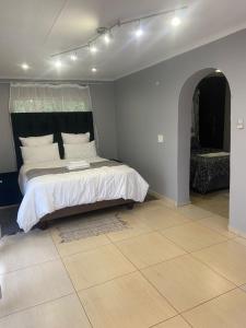 Un dormitorio con una cama grande con almohadas blancas. en Hazel Nest Ezulwini, en Ezulwini